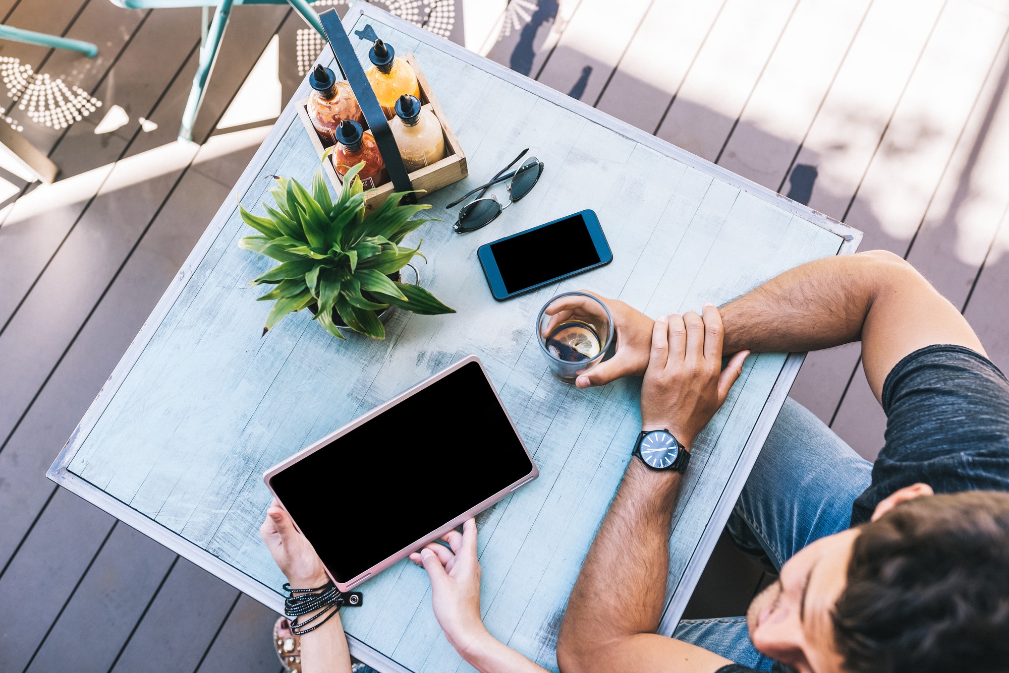 Top view of people with gadgets on a table outside